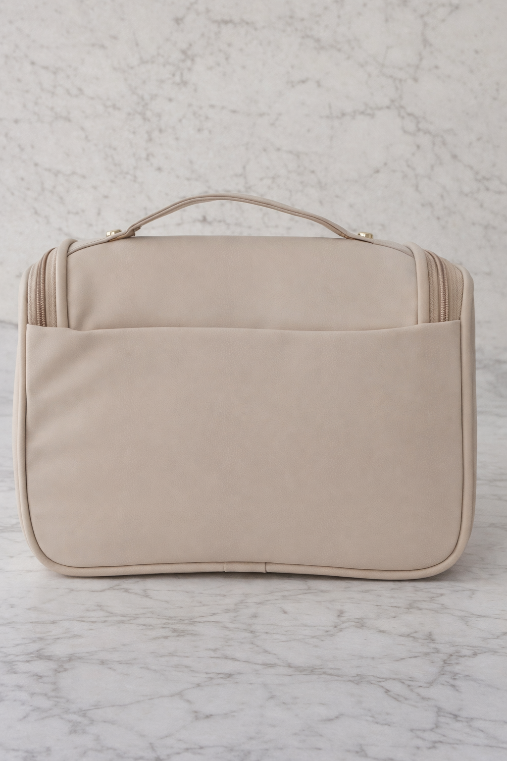 Beige quilted beauty case on a marble surface